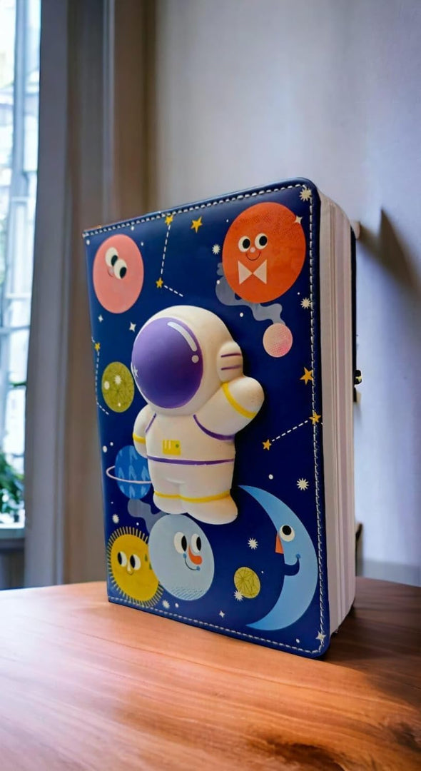 Notebook with a space-themed cover featuring an astronaut and planets on a wooden surface.