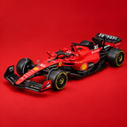 A red and black Ferrari Formula 1 race car with visible Shell, Pirelli, and other sponsor logos, photographed on a solid red studio background.