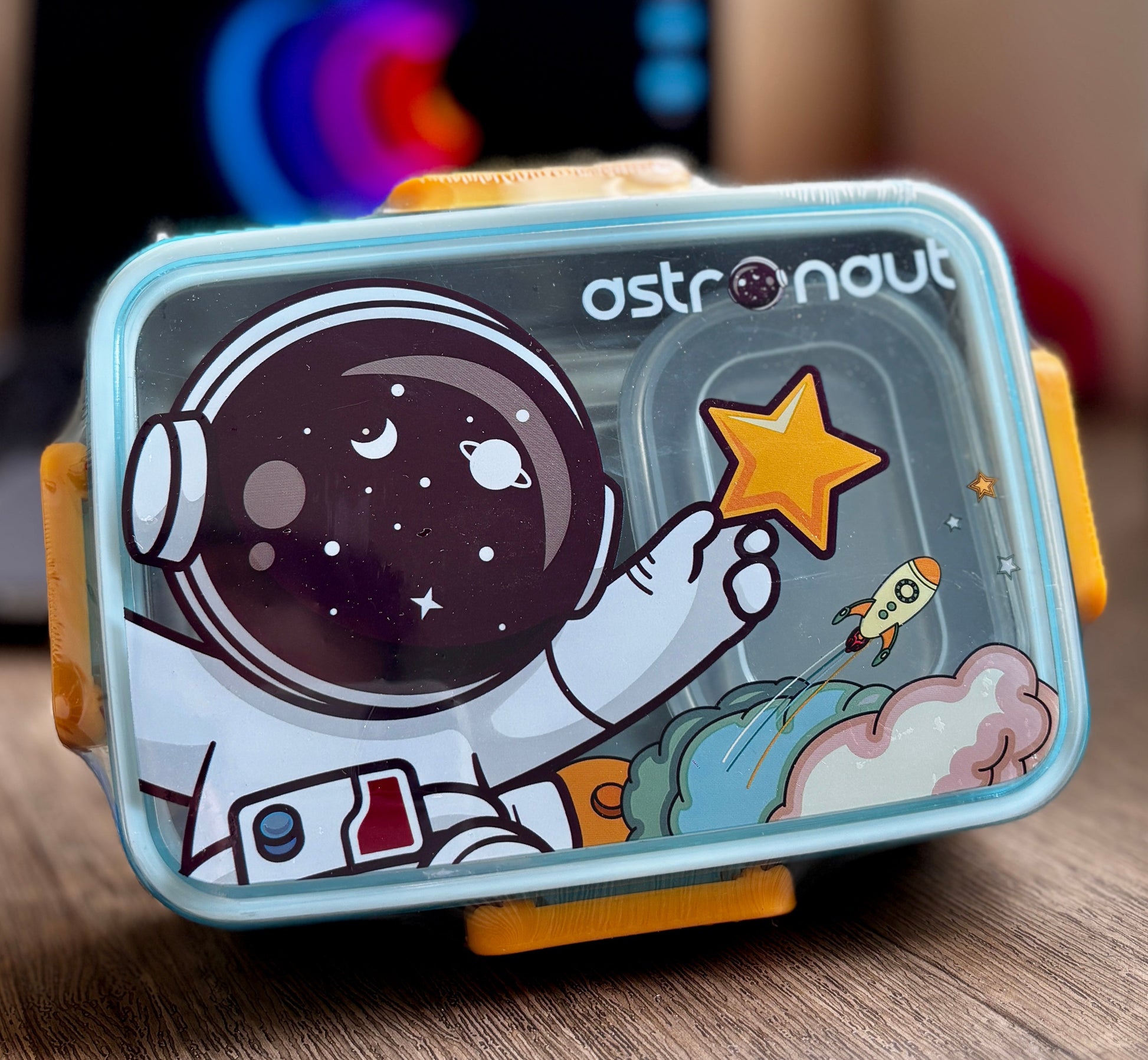 Children's lunchbox with astronaut design on a wooden surface